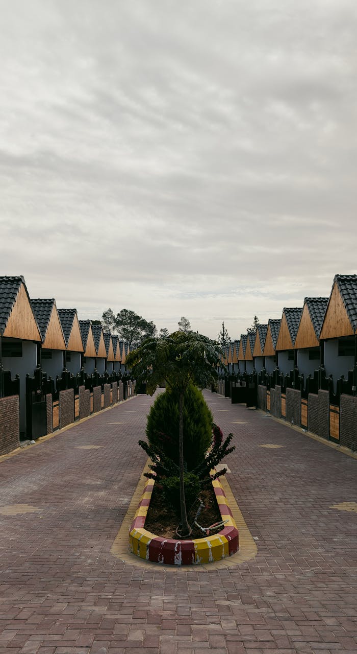 A row of modern houses with geometric roofs and cloudy skies overhead, offering a symmetrical and architectural view.